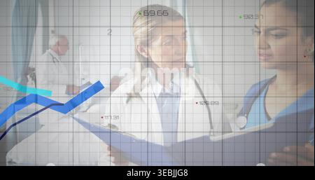 Reviewing clinicians in scrubs with blue chart in hospital corridor, stethoscope, data overlay Stock Photo