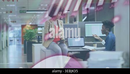 Discussing project two colleagues in biz-casual attire consulting at office with laptop and tablet Stock Photo