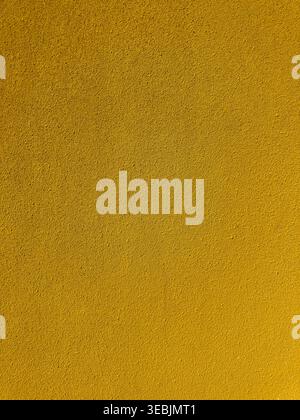Close up view of a vibrant yellow abrasive surface with a grainy sand like texture. The uniform lighting highlights the fine grit and porous details o Stock Photo