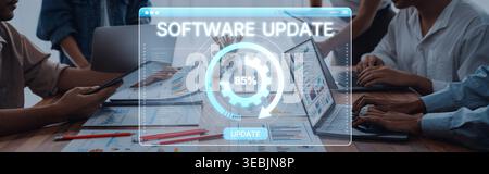 A dedicated team collaborates in a modern office setting, focusing on a software update. Progress is tracked through digital interfaces and charts Stock Photo