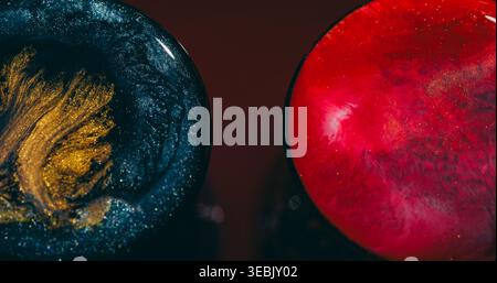 Glitter sphere. Fluid splatter. Defocused pink blue golden splash symmetrical ink liquid floating on abstract red maroon bokeh background. Stock Photo