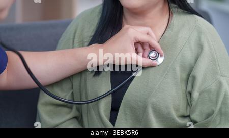Asian healthcare professional using stethoscope on woman patient Stock Photo