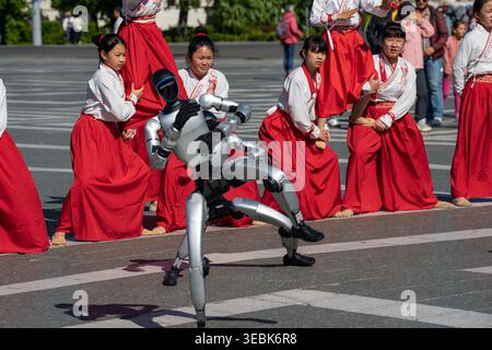 Budapest, Hungary - April 26, 2026: A striking close-up action shot of a silver bipedal robot performing a balanced dance move, set against a backdrop Stock Photo