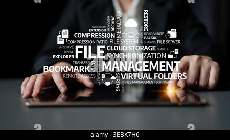 A close-up view of hands using a tablet surrounded by digital words representing file management concepts, highlighting organization, cloud storage Stock Photo