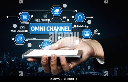 A hand holds a smartphone displaying an omni channel strategy with icons for social media and mobile apps, highlighting modern customer engagement and Stock Photo