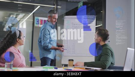 Pointing and writing man in light blue shirt presenting at modern office meeting, with flip chart Stock Photo