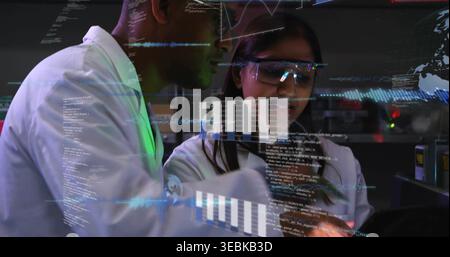 Examining researchers in lab coats wearing safety glasses, studying handheld tablet at lab bench Stock Photo