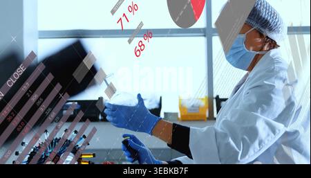 Handling pipette and flask, lab tech wearing lab coat, gloves working at bench with data overlays Stock Photo