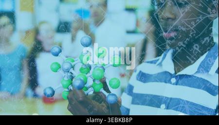 Holding studying boy in striped polo with ball-and-stick model equations overlay in lab, copy space Stock Photo