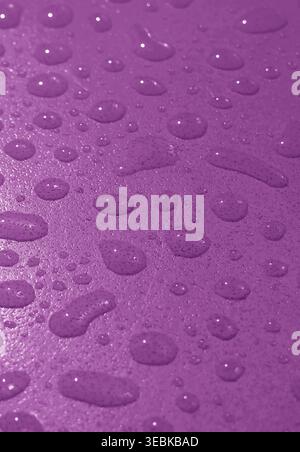 Closeup of water droplets on deep purple colored tabletop after the rain Stock Photo