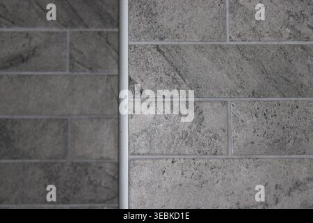 The photograph shows gray tiles arranged in two different patterns on a wall. The tiles are indoors, with clear natural light coming in during the day Stock Photo