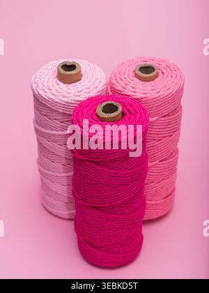 Three spools of thread in various shades of pink, arranged on a light pink background. Stock Photo