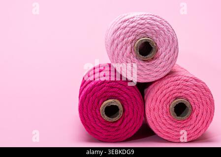 Three spools of thread in various shades of pink, arranged on a light pink background. Stock Photo