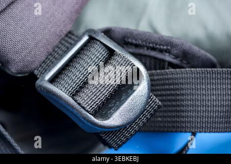 Macro closeup showing black plastic buckle fastener holding nylon strap on outdoor backpack giving reliable secure feeling of strong durable equipment Stock Photo