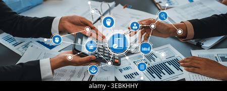 A dynamic business scene featuring two professionals collaborating on financial insights, using a calculator and reviewing documents on a sleek office Stock Photo