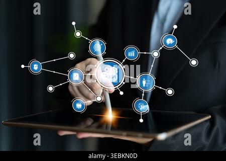 A business professional engages with a tablet displaying dynamic digital network icons, illustrating connectivity and technology in the modern Stock Photo