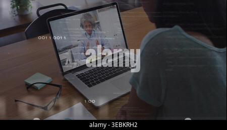 Sitting man in teal-shirt watching call on laptop at wooden table with eyeglasses, copy space Stock Photo