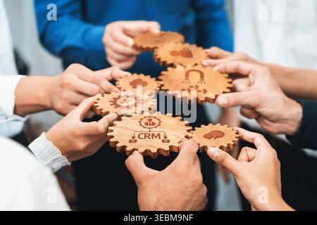A diverse group of hands holding intricately designed wooden gears representing collaboration, business strategy, and effective project management in Stock Photo
