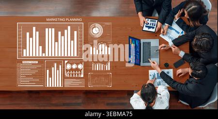 A vibrant marketing planning session depicting a diverse business team analyzing data and strategies. The group collaborates over charts and laptops Stock Photo