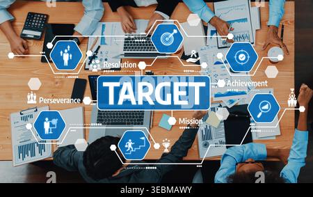 A diverse professional team collaborates at a workspace, focusing on strategic business objectives, illustrated by icons representing perseverance Stock Photo