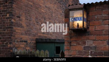 Vintage Cinema Lantern On Brick Wall Beside Green Gate in Old Alley Evening Light Stock Photo