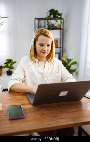 Woman working intently on a laptop in a bright room Stock Photo