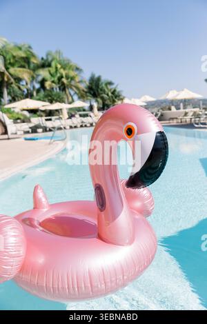 Pink inflatable flamingo float floating in a blue swimming pool Stock Photo