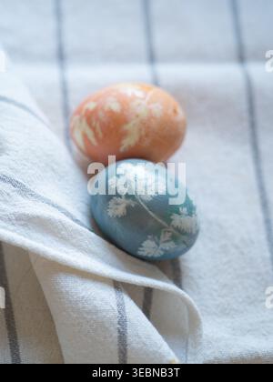 Blue and Orange Easter Eggs with Floral Imprints on White Linen Stock Photo