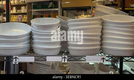 Stacks of White Ceramic Bowls on Store Shelf in Kitchenware Shop Display Stock Photo