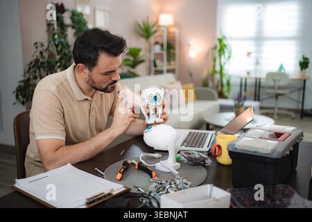 Man assembling a smart home security camera on a table with a laptop and tools Stock Photo