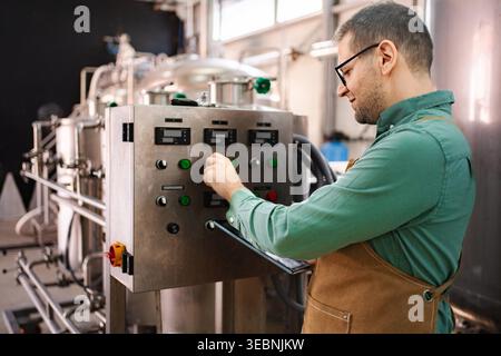 Man operating industrial machinery control panel in a craft brewery Stock Photo