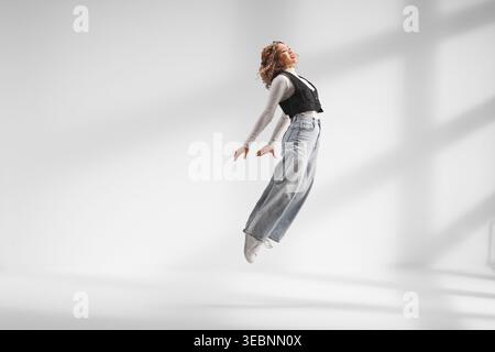Asian young woman jumping in a studio with shadows on the wall Stock Photo