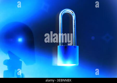 Close-up of a futuristic robot head in a modern blue-toned environment, illuminated with cinematic light flares. A padlock placed nearby symbolizes cy Stock Photo