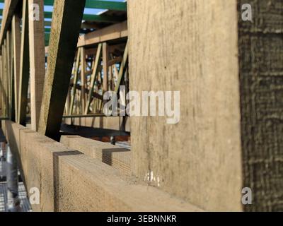 Close perspective along wooden beams and trusses showing structural framing details inside unfinished building. Construction, carpentry, engineering, Stock Photo