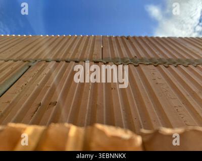 Clay hollow blocks with ribbed surface installed in wall construction under blue sky view from below. Construction, masonry, building materials, archi Stock Photo