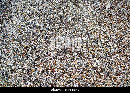 High-angle close-up of multicolored small pebbles and natural gravel. This organic stone texture represents zen wellness, sustainable landscaping, and Stock Photo