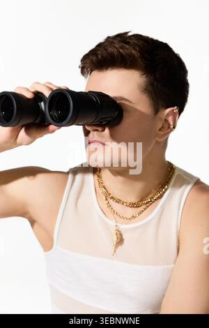 A fashionable young man enjoys summertime while using binoculars to gaze at the scenery around him. Stock Photo