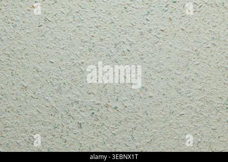 Close-up of light speckled textured surface with green and beige fibers Stock Photo