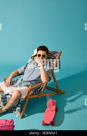 Charming young man relaxes on a sunny day, sipping a cool drink by a colorful skateboard. Stock Photo