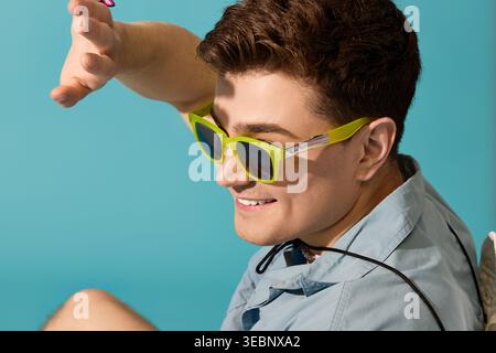 Young man relaxes in summer style, wearing stylish sunglasses and having a great time outdoors. Stock Photo
