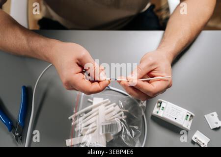 Top view of technician male fixing electrical wire, stripping insulation from cable, performing maintenance, working on home repair or diy technology Stock Photo