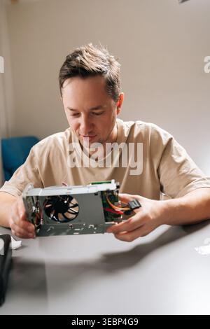 Portrait of skilled repairman completing electronic repairs in professional workshop, holding disassembled hardware, exposing intricate internal Stock Photo