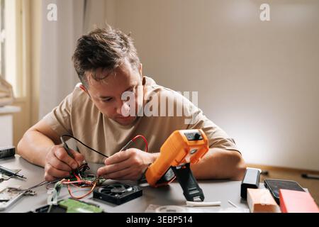 Skilled technician using multimeter to diagnose electronic circuit board, troubleshooting computer hardware, installing parts, repairing modern Stock Photo