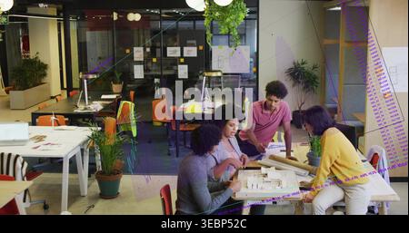 Pointing woman in light blazer leading team, leaning members inspecting scale model, plans, studio Stock Photo