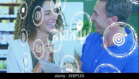 Smiling woman in cardigan and man in blue shirt holding brochure in pharmacy, with AR graphics Stock Photo
