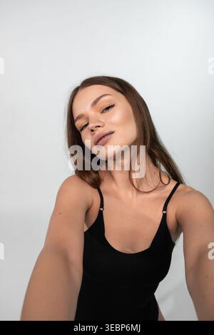Young woman taking a selfie, capturing natural beauty and self-confidence with a minimalist background Stock Photo