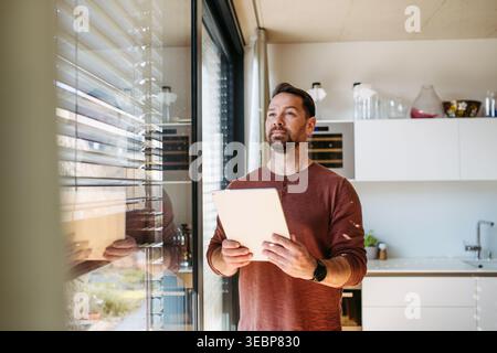 Man using smart home app to control electric window shades indoors. Stock Photo
