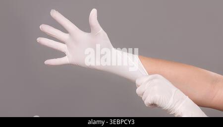 Doctor putting on sterile gloves on grey Stock Photo