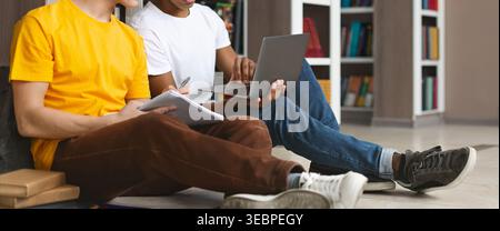 Two Students Studying Together on the Floor With Laptops and Notebooks in a Library Stock Photo