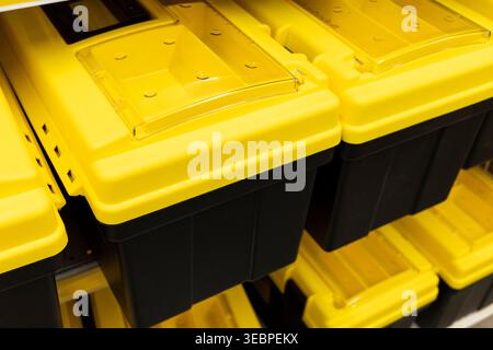 yellow plastic storage bins stacked in retail store aisle, organized container system detail. Concept: storage organization Stock Photo